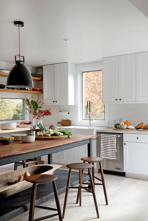 a modern white kitchen plus a large kitchen island table in black and with a wooden tabletop