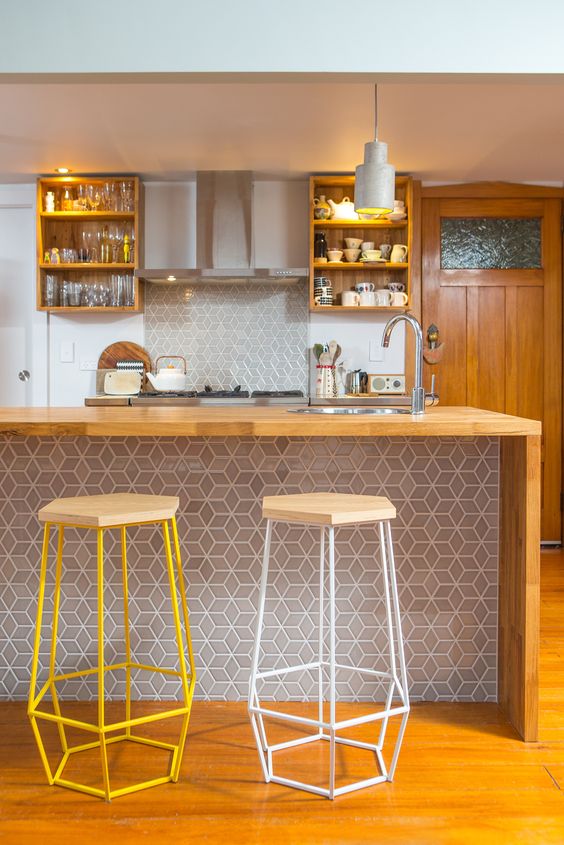 a stylish bar counter clad in geometric tiles that echo the backsplash and wood with geometric stools