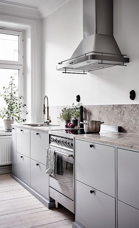a Scandinavian kitchen with black touches, a stone backsplash and counters looks ethereal