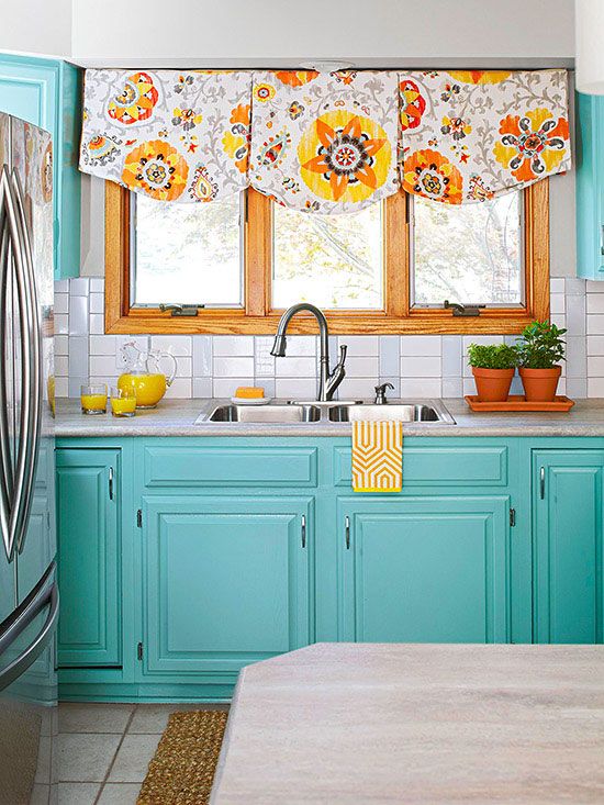 colorful blue cabinets and bold floral curtains make the kitchen look like springtime
