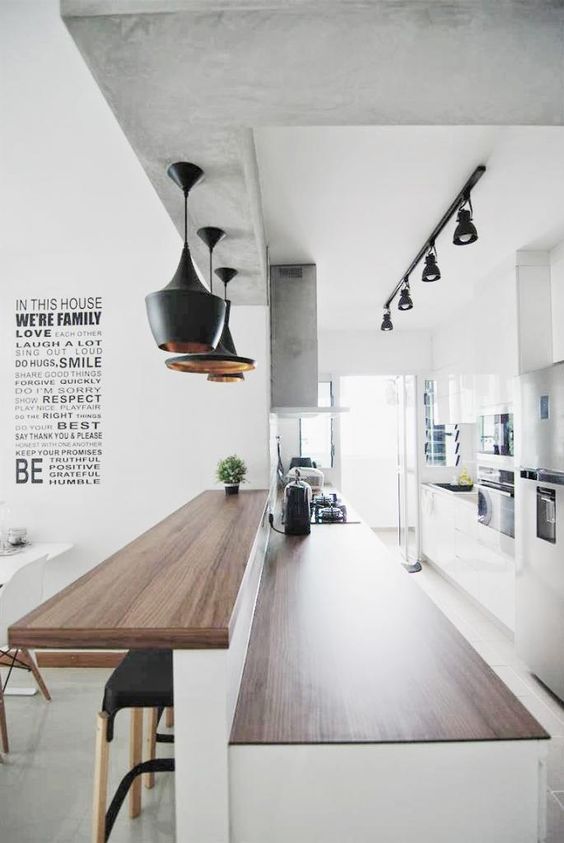 a large bi level kitchen bar includes an eating space and a kitchen island and is accented with pendant lamps