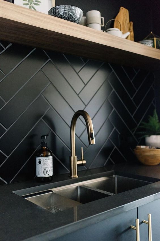 una placa para salpicaduras de espiga de cocina de azulejos negros es una idea elegante para un espacio moderno