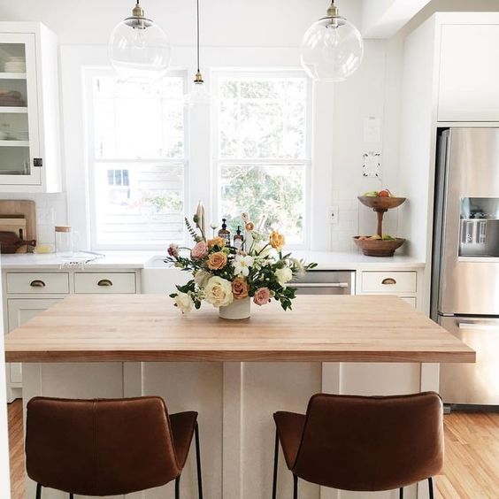 a welcoming space with a wooden tabletop kitchen island and dining table in one, leather stools for sitting
