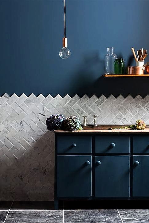 navy blue cabinets and a wall marble tiles lined with a chevron pattern
