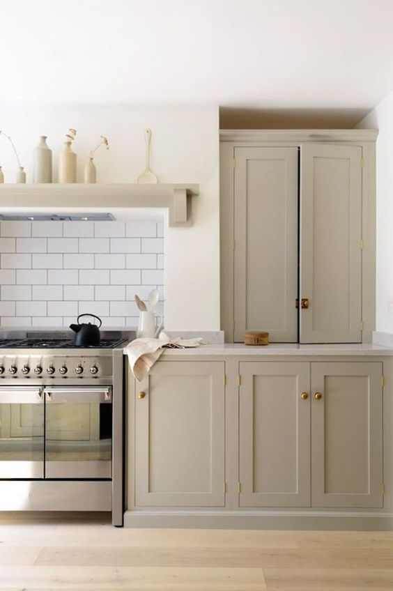 a beautiful greige kitchen with shaker cabinets, white stone countertops and a white subway tile backsplash plus touches of copper