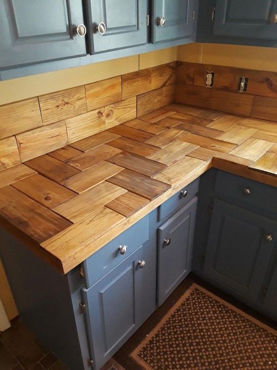 a creative wooden tile kitchen countertop plus backsplash contrast the blue cabinets and add warmth to the space