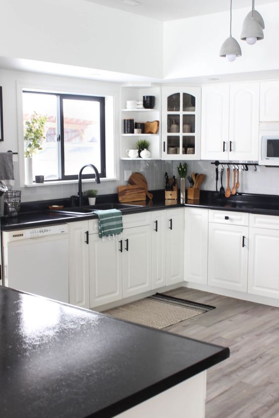 stylish white kitchen cabinets accented with dark stained countertops and black hardware for a bold look